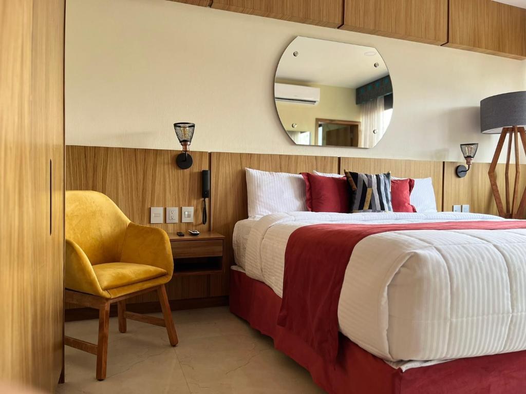 Hotel room with white bedding, warm wood finishes and a yellow chair